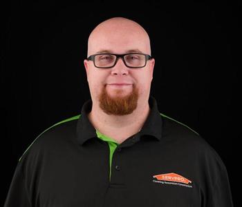 Man wearing a black SERVPRO shirt who is bald and smiling.